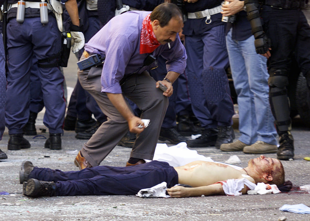 Il corpo di Carlo Giuliani morto in piazza Alimonda a Genova, circondato dagli agenti di polizia. Luca Zennaro