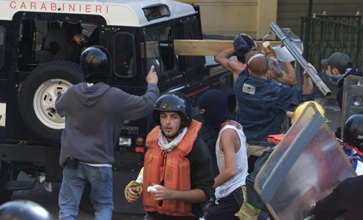 A CARABINIERE POINTS A GUN AS PROTESTERS ATTACK THEIR VEHICLE